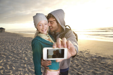 Junges Paar macht ein Selfie am Strand bei Sonnenaufgang - TOYF000417