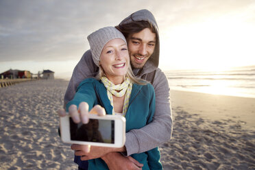 Junges Paar macht ein Selfie am Strand bei Sonnenaufgang - TOYF000419