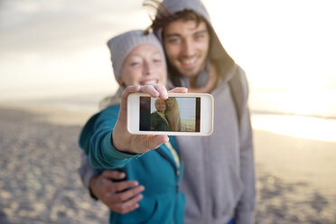 Junges Paar macht ein Selfie am Strand bei Sonnenaufgang - TOYF000421
