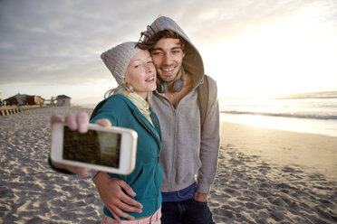Junges Paar macht ein Selfie am Strand bei Sonnenaufgang - TOYF000422