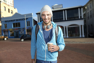 Porträt eines lächelnden jungen Mannes mit Kaffee zum Mitnehmen - TOYF000449