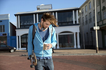 Young man holding coffee to go and longboard - TOYF000450