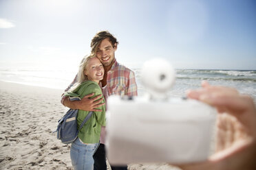 Glückliches junges Paar am Strand wird fotografiert - TOYF000615