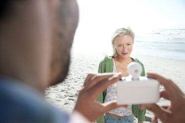 Mann fotografiert eine lächelnde Frau am Strand - TOYF000478