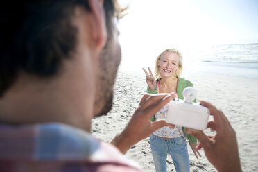 Mann fotografiert eine glückliche Frau am Strand - TOYF000479