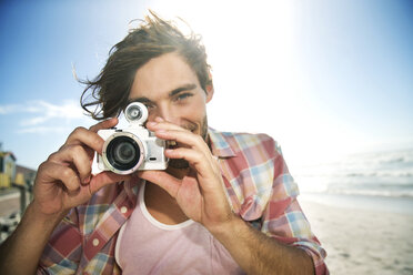 Junger Mann beim Fotografieren am Strand - TOYF000481