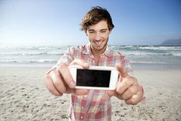 Junger Mann macht Selfie am Strand - TOYF000482