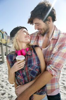Glückliches junges Paar, das sich am Strand umarmt - TOYF000496