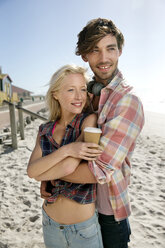 Glückliches junges Paar, das sich am Strand umarmt - TOYF000498