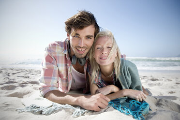 Glückliches junges Paar am Strand liegend - TOYF000506