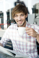 Portrait of smiling young man in a cafe - TOYF000521