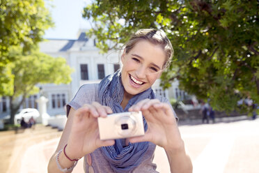Porträt einer glücklichen jungen Frau mit Kamera - TOYF000526
