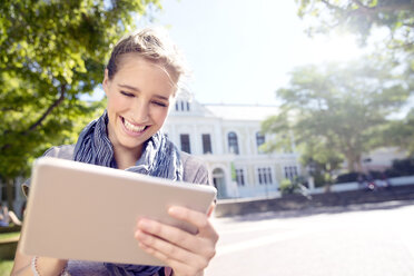 Glückliche junge Frau, die ein digitales Tablet im Freien benutzt - TOYF000529