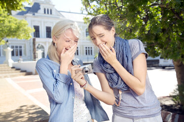 Two laughing young women outdoors looking at camera - TOYF000534