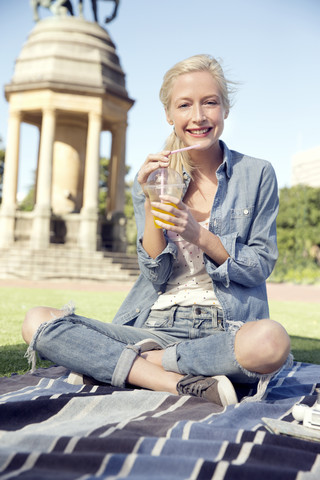 Junge Frau im Park mit Erfrischungsgetränk, lizenzfreies Stockfoto