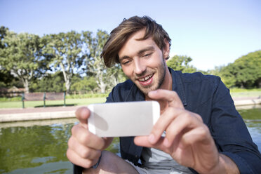 Lächelnder junger Mann im Park, der ein Selfie macht - TOYF000567