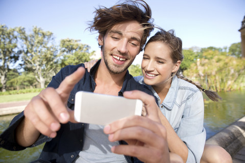 Glückliches junges Paar im Park macht ein Selfie, lizenzfreies Stockfoto