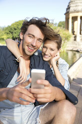 Glückliches junges Paar im Park macht ein Selfie - TOYF000569