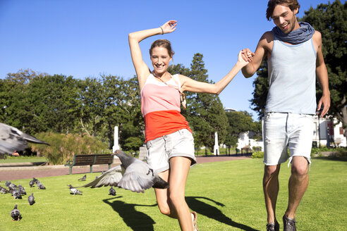 Enthusiastisches junges Paar jagt Tauben im Park - TOYF000572