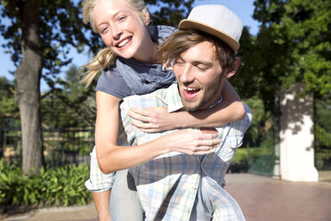 Happy young man carrying girlfriend piggyback - TOYF000577
