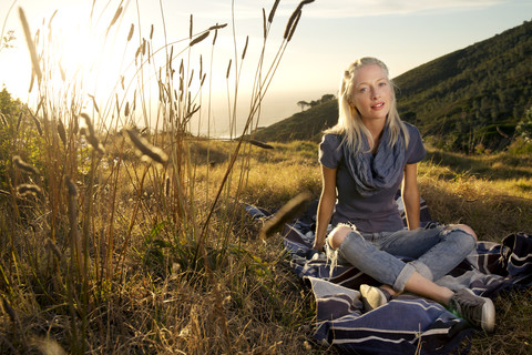 Junge Frau entspannt sich auf einer Decke auf einer Wiese, lizenzfreies Stockfoto