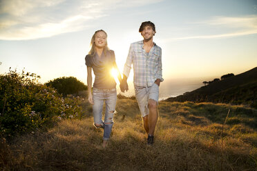 Junges Paar spaziert Hand in Hand an der Küste - TOYF000606
