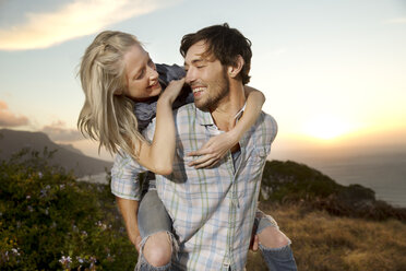 Young man carrying girlfriend piggyback at the coast - TOYF000611