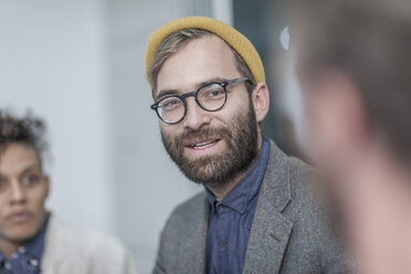 Man with glasses and yellow beanie in meeting with collegues - ZEF005725