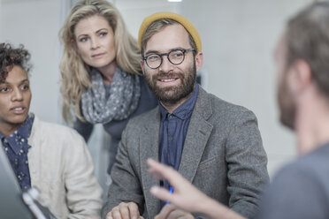 Man with glasses and yellow beanie in meeting with collegues - ZEF005726