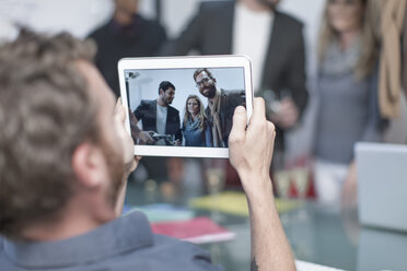 Man taking a photo of colleagues on a digital tablet - ZEF005994