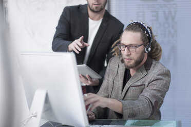 Mann spricht über ein Headset hinter einem Computer - ZEF005769