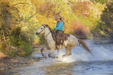 USA, Wyoming, Cowgirl reitet auf seinem Pferd über den Fluss - RUEF001590