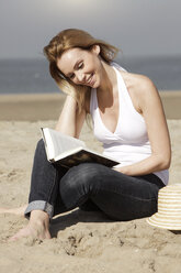 Netherlands, Scheveningen, young woman reading book on the beach - GDF000723
