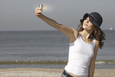 Netherlands, Scheveningen, young woman taking a selfie on the beach - GDF000726