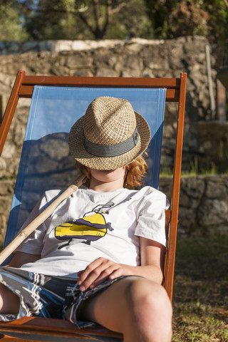 Griechenland, Korfu, Junge mit Hut im Liegestuhl, lizenzfreies Stockfoto