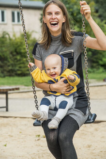 Mutter sitzt mit ihrem kleinen Sohn auf einer Schaukel - FBF000395