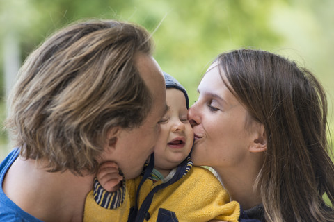 Vater und Mutter küssen ihren kleinen Sohn, lizenzfreies Stockfoto