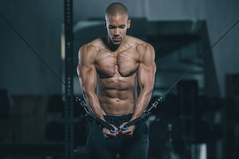 Junger Mann trainiert Brustmuskeln am Kabelkreuz im Fitnessstudio, lizenzfreies Stockfoto