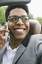 Junger schwarzer Mann sitzt im Cabrio und telefoniert - ABZF000045