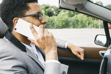 Young black man sitting in convertible, talking on the phone - ABZF000046