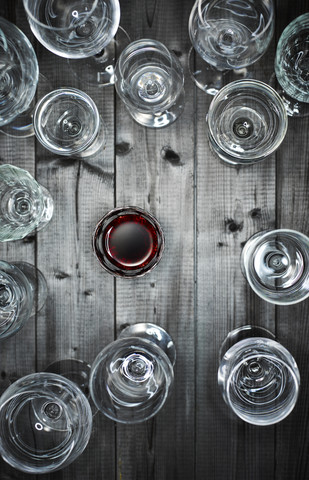 Glas Rotwein und leere Weingläser auf Holz, lizenzfreies Stockfoto