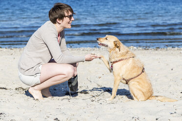 Deutschland, Kiel, Frau mit Hund am Sandstrand - JFEF000674
