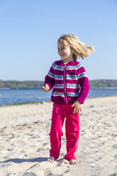 Deutschland, Kiel, glückliches kleines Mädchen am Sandstrand stehend - JFEF000669