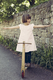 Little girl balancing on an old wooden scooter - LVF003391