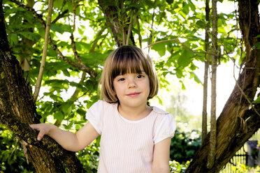 Porträt eines lächelnden kleinen Mädchens, das auf einen Baum klettert - LVF003392