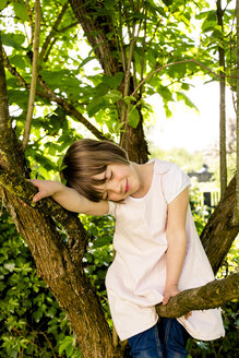 Portrait of smiling little girl with closed eyes sitting on a branch - LVF003393