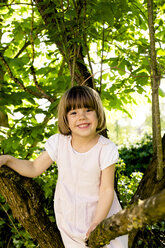 Porträt eines lächelnden kleinen Mädchens, das auf einen Baum klettert - LVF003394