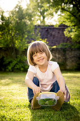 Little girl with insect can sitting on a meadow - LVF003399