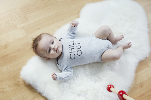 Baby auf Fell auf dem Boden liegend, lizenzfreies Stockfoto