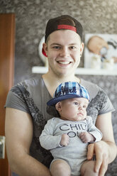 Portrait of smiling young father holding baby - STKF001274